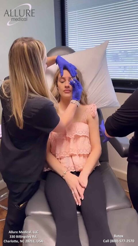 A patient receives a Botox treatment from a medical professional at Allure Medical in Charlotte, NC. The patient is seated in a chair, with another professional assisting.