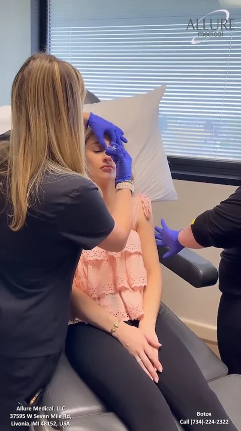 A person is getting an injection on their forehead by a medical professional wearing blue gloves at Allure Medical clinic. The clinic's contact information is visible on the image.