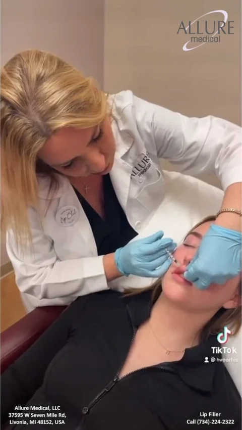 A medical professional in a white coat administers a lip filler injection to a patient lying down. The setting is Allure Medical in Livonia, MI, with contact information displayed on the image.